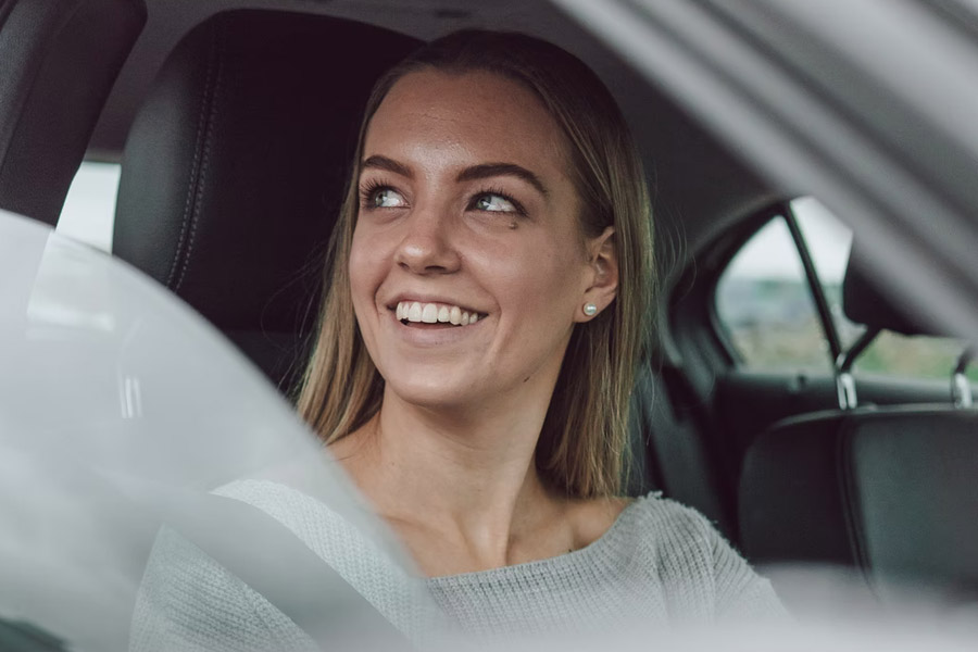 Young woman sitting in car smiling